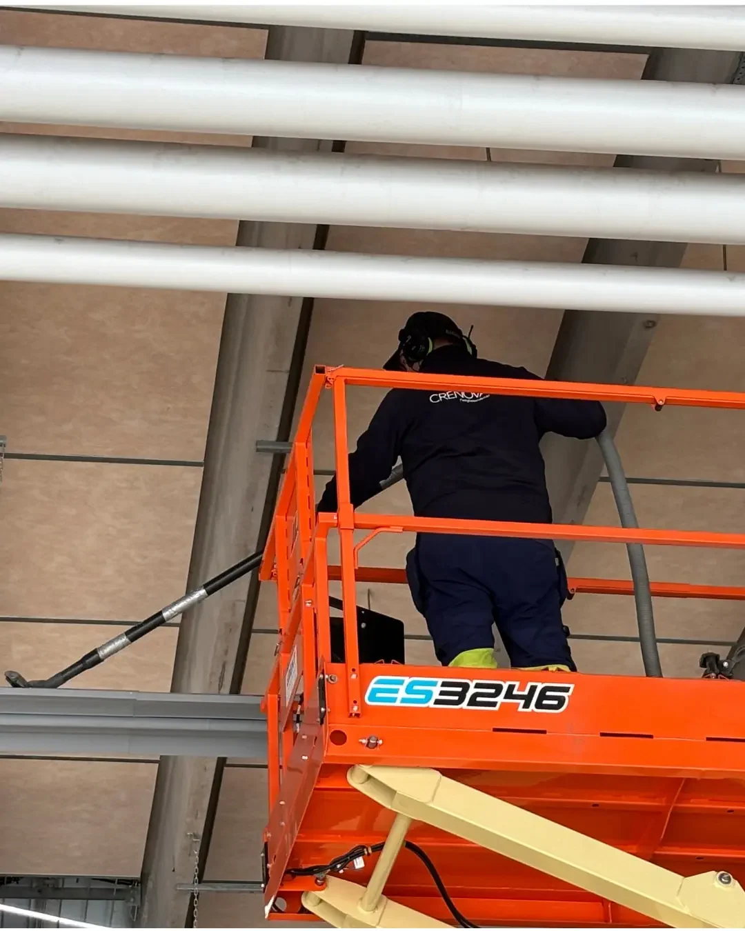 Arbetare på byggnadsställning rengör takstrukturer med en långslang.