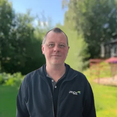 Man står utomhus i en trädgård med grönska. Kontakt.